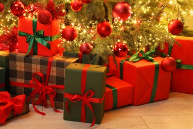 Photo of Many gift boxes under decorated Christmas tree indoors