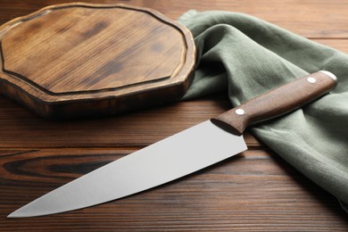 Photo of Knife, board and towel on wooden table