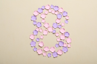 Number 8 made with paper flowers on beige background, flat lay. International Women's day