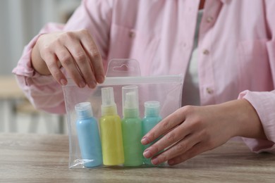 Woman with cosmetic travel kit at wooden table, closeup. Bath accessories