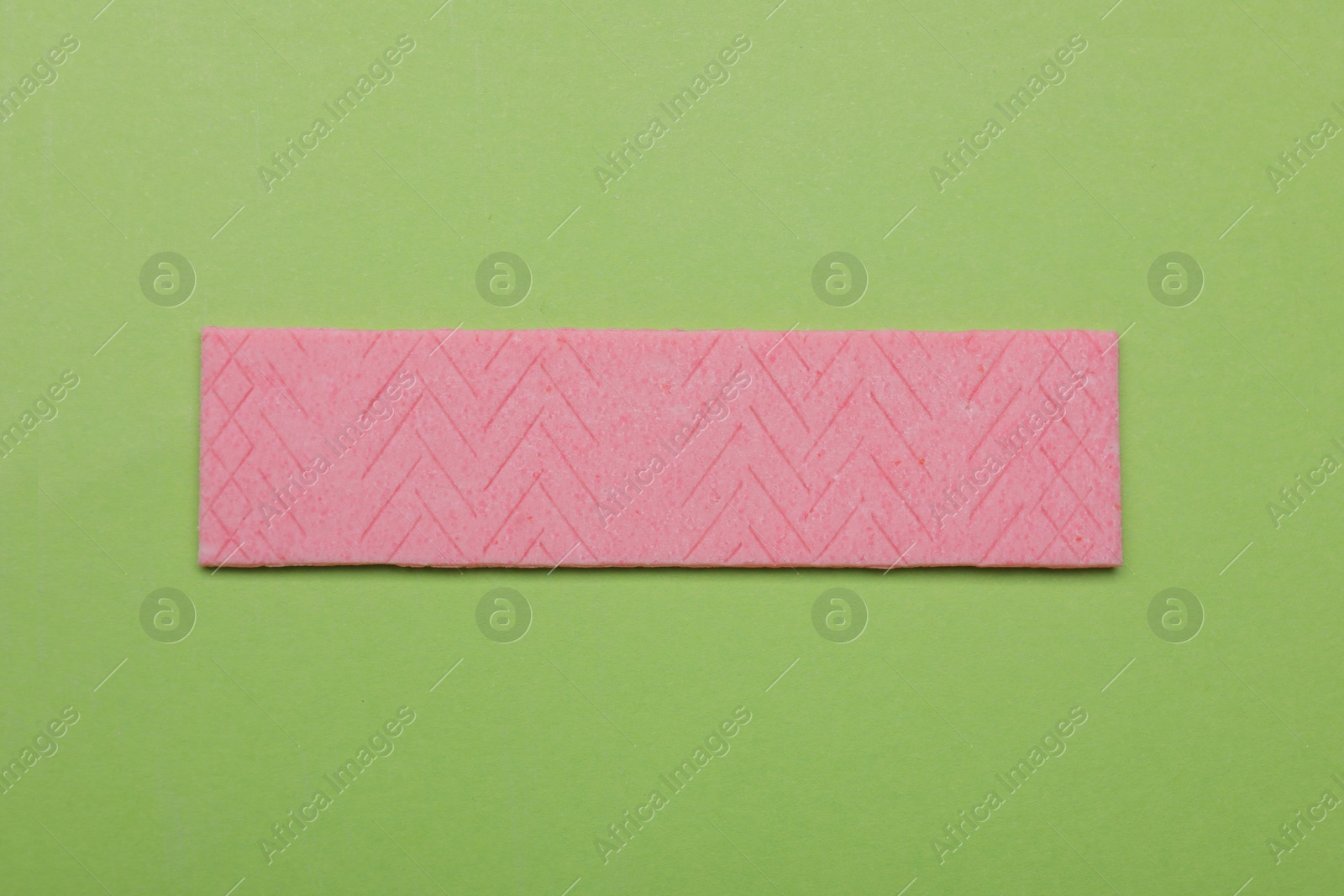 Photo of One stick of tasty chewing gum on light green background, top view