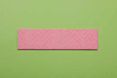 Photo of One stick of tasty chewing gum on light green background, top view