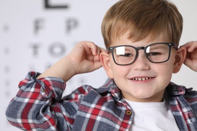 Little boy with glasses against vision test chart