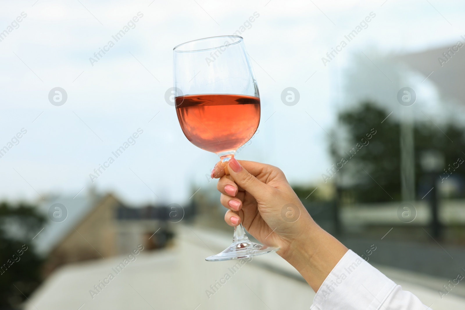 Photo of Woman holding glass of rose wine outdoors, closeup