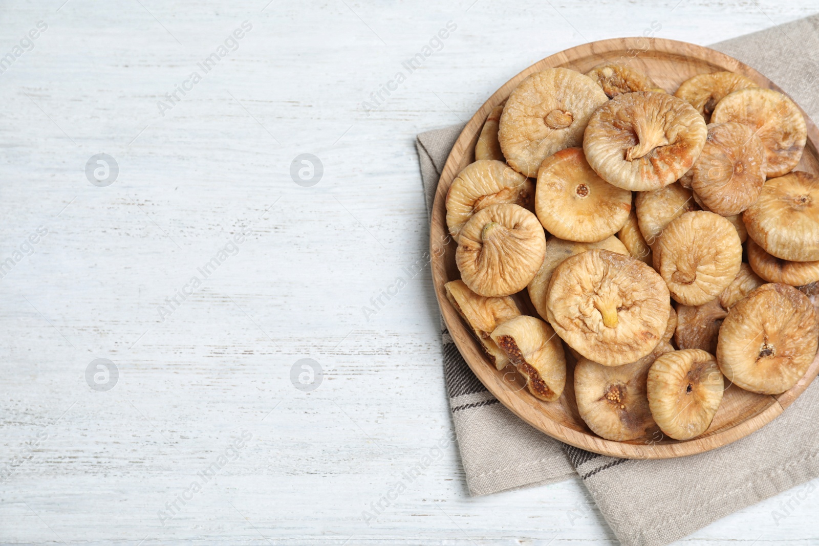 Photo of Tasty dried figs on white wooden table, top view. Space for text