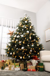 Beautiful Christmas tree and many gifts near window in living room, low angle view