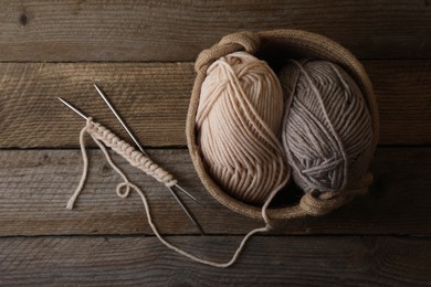 Photo of Soft colorful yarns, knitting and metal needles on wooden table, top view