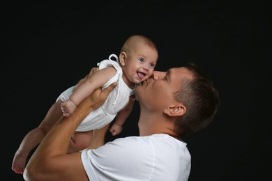 Happy father kissing his little baby on black background