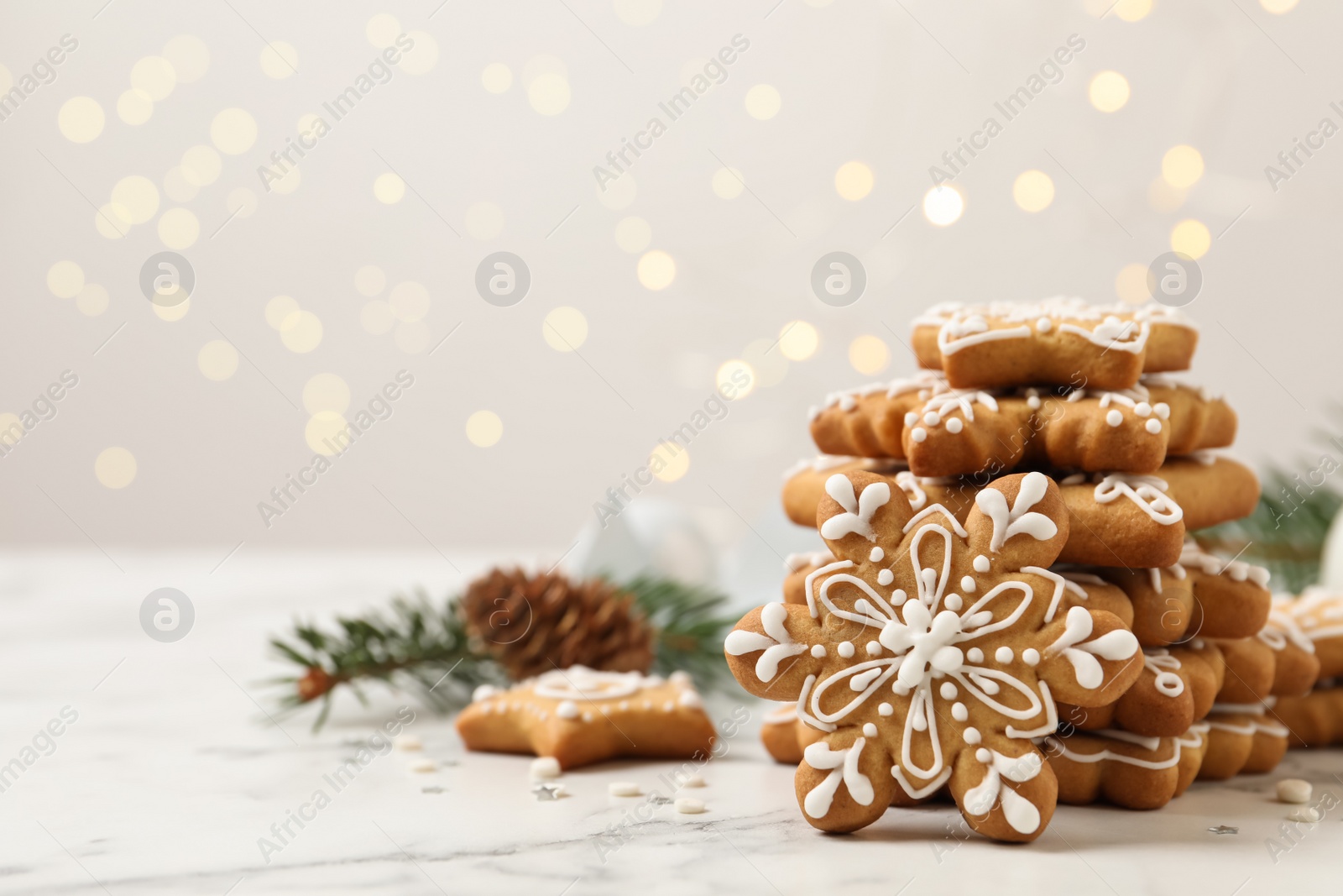 Photo of Tasty Christmas cookies on white marble table against blurred festive lights, space for text