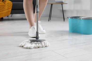 Photo of Woman cleaning floor with mop indoors, closeup