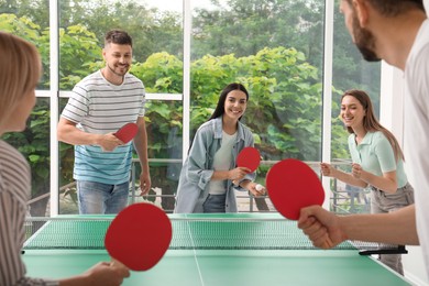 Happy friends playing ping pong together indoors