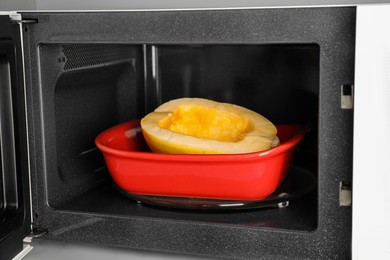 Photo of Baking dish with half of fresh spaghetti squash in microwave oven