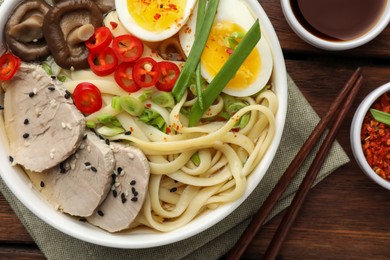 Photo of Delicious ramen with meat in bowl served on wooden table, flat lay. Noodle soup