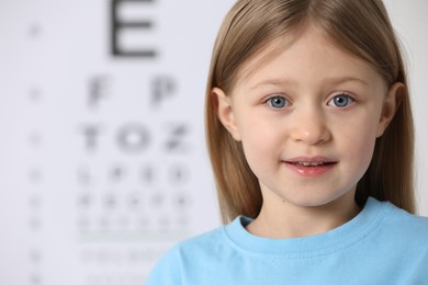 Cute little girl against vision test chart
