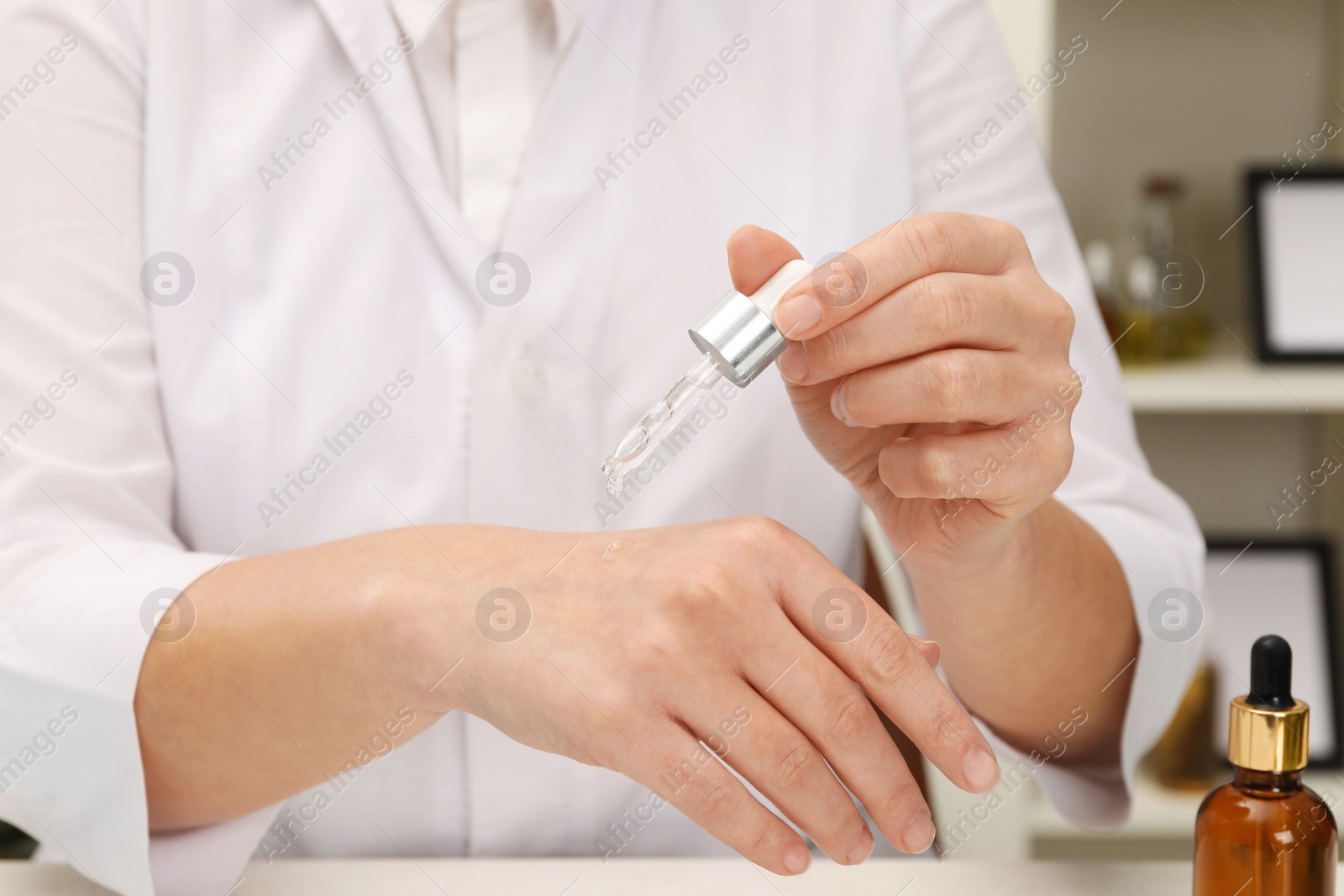 Photo of Dermatologist testing cosmetic product at table indoors, closeup