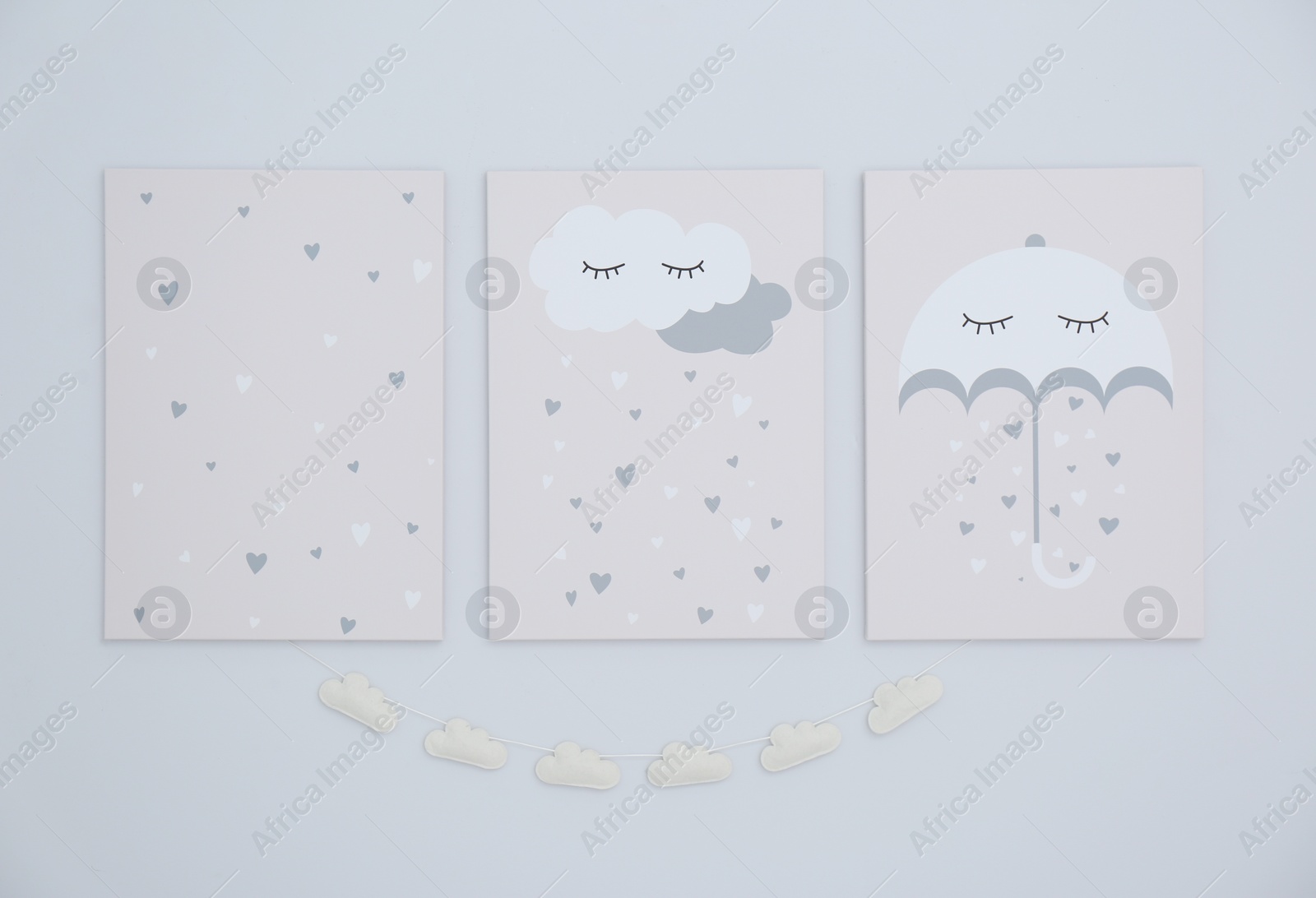 Photo of Cute posters and cloud garland on light wall. Interior elements