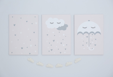 Photo of Cute posters and cloud garland on light wall. Interior elements