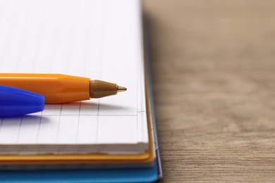 Ballpoint pen and notebook on wooden table, closeup. Space for text