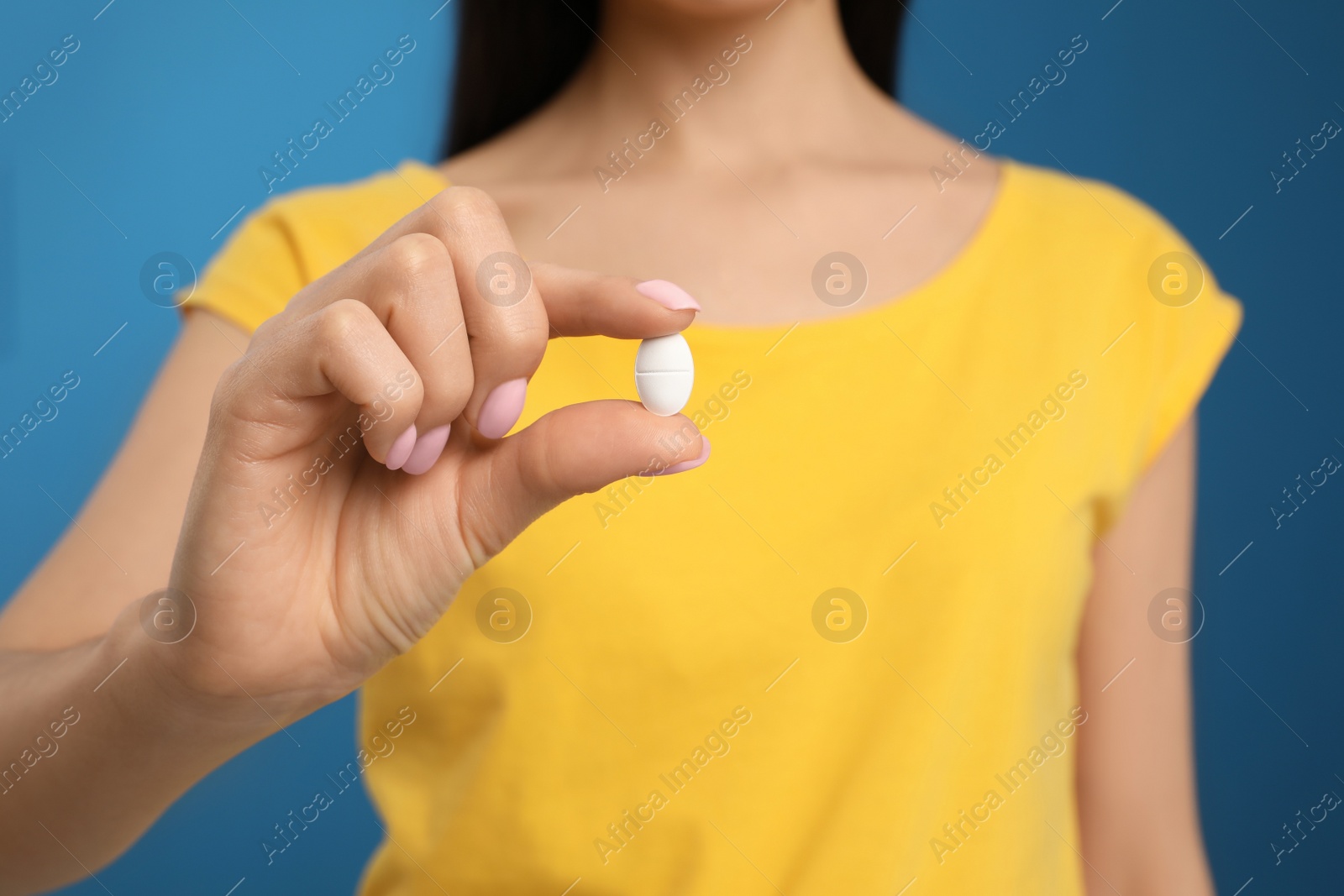 Photo of Woman with vitamin pill on blue background, closeup