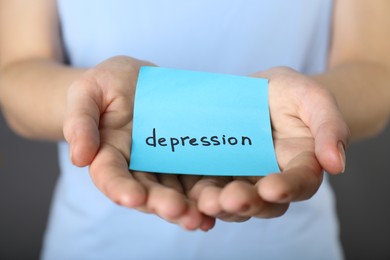 Photo of Woman holding sticky note with word Depression, closeup