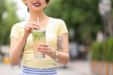 Photo of Young woman with cup of tasty lemonade outdoors