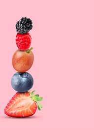 Stack of different fresh tasty berries on pink background, space for text