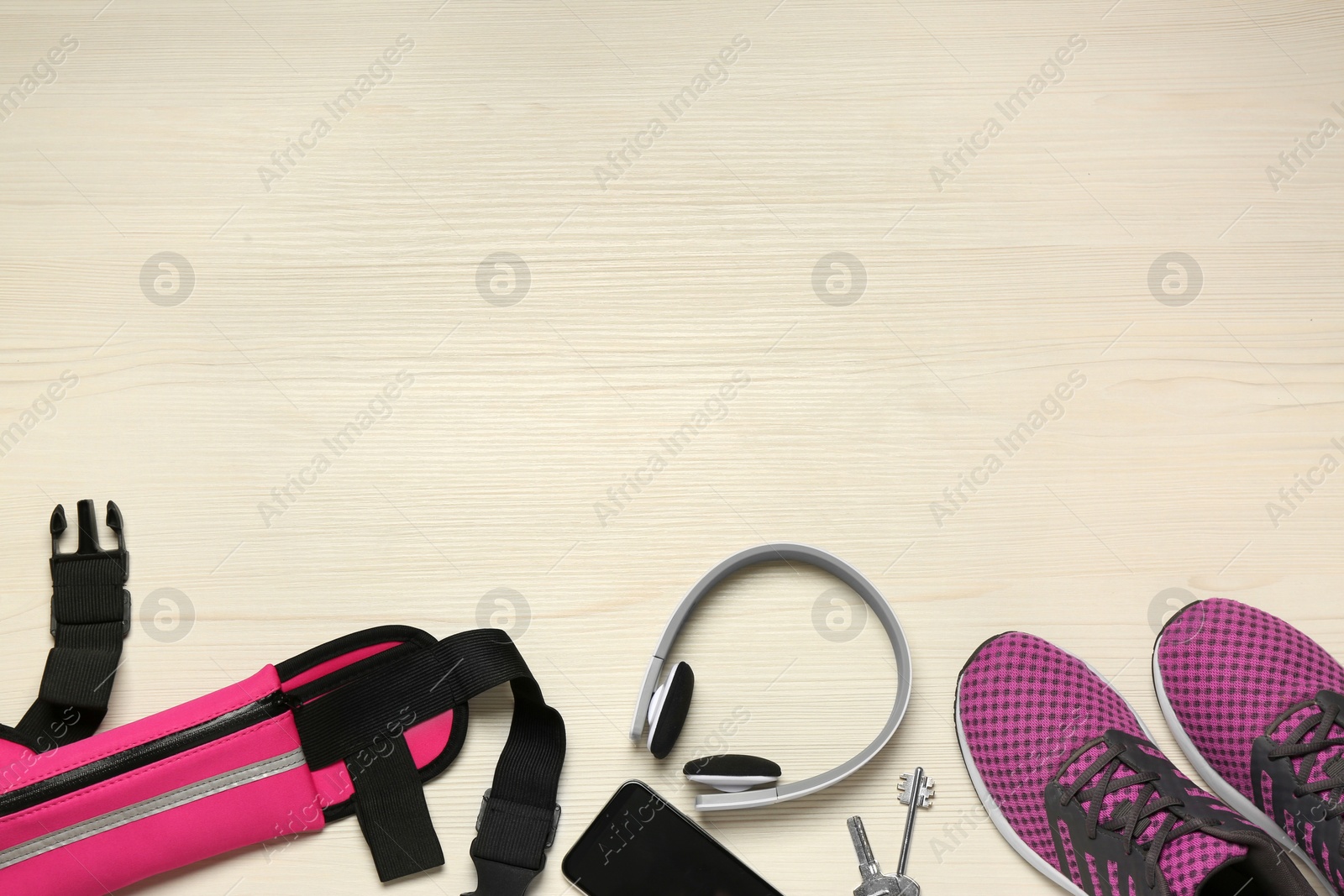 Photo of Flat lay composition with pink waist bag on white wooden table, space for text