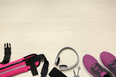 Flat lay composition with pink waist bag on white wooden table, space for text