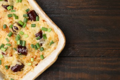 Photo of Tasty sausage casserole with green onions in baking dish on wooden table, top view. Space for text