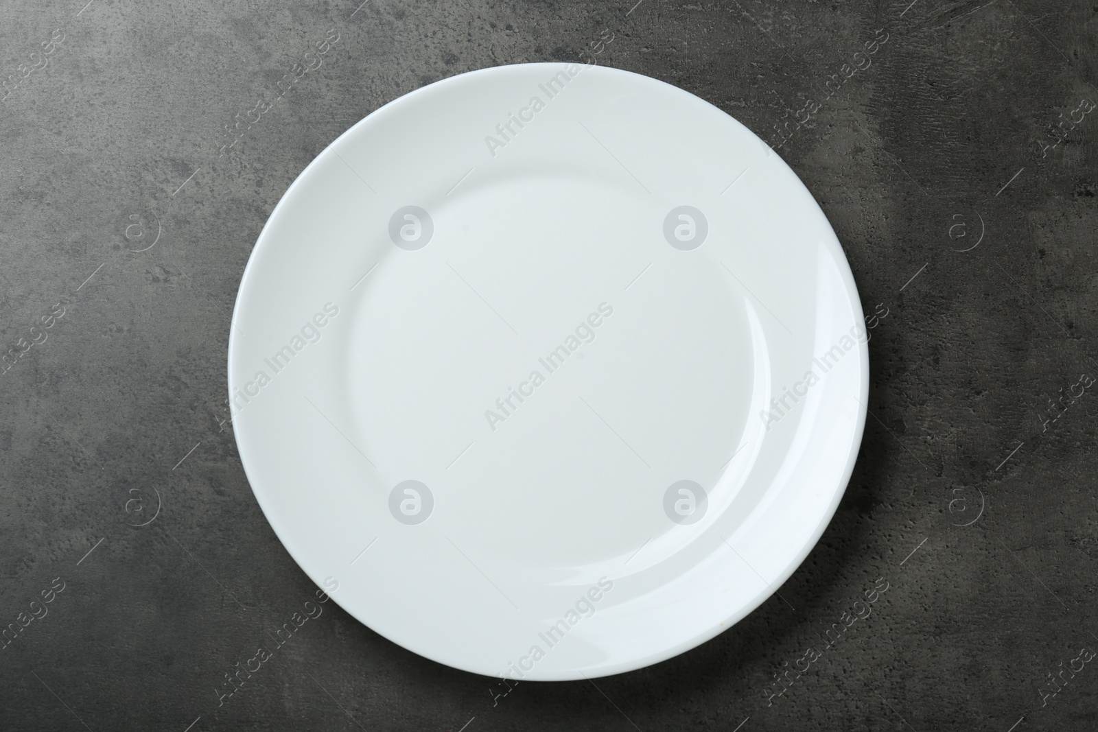 Photo of Empty white ceramic plate on grey table, top view