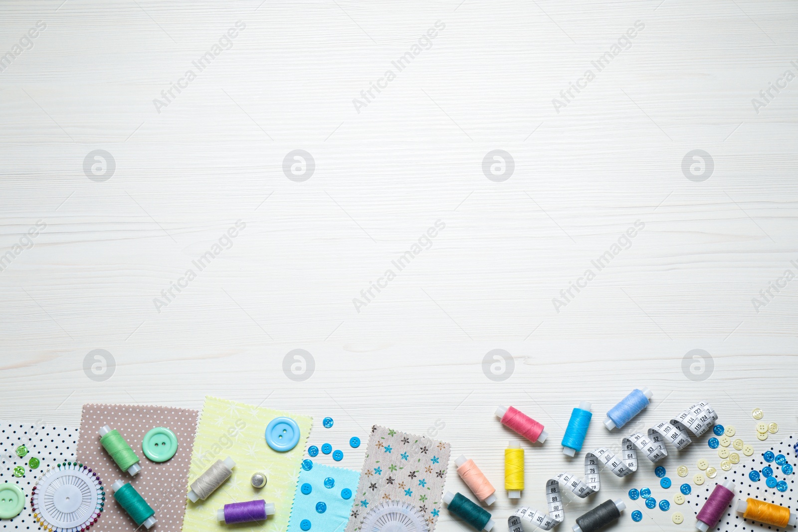 Photo of Different sewing items on white wooden background, flat lay. Space for text