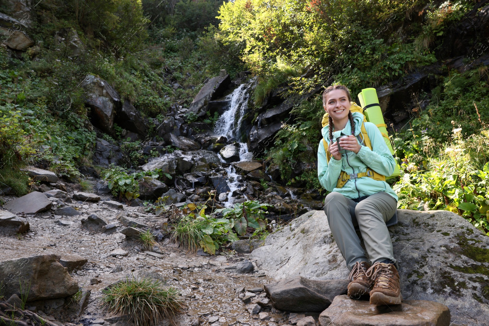 Photo of Tourist with cup near waterfall in mountains. Space for text