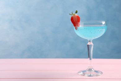 Photo of Tasty light blue cocktail on pink wooden table, space for text