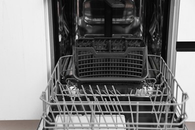 Open clean empty dishwasher indoors, closeup. Home appliance