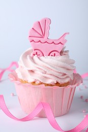 Beautifully decorated baby shower cupcake for girl with pink cream and topper on light background, closeup