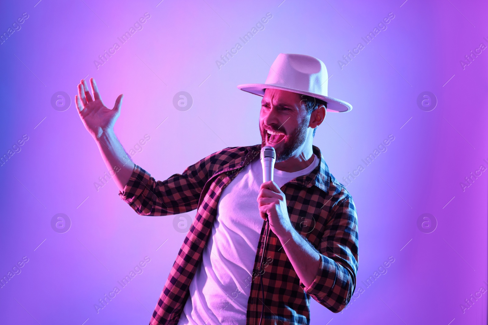 Photo of Emotional man with microphone singing in neon lights