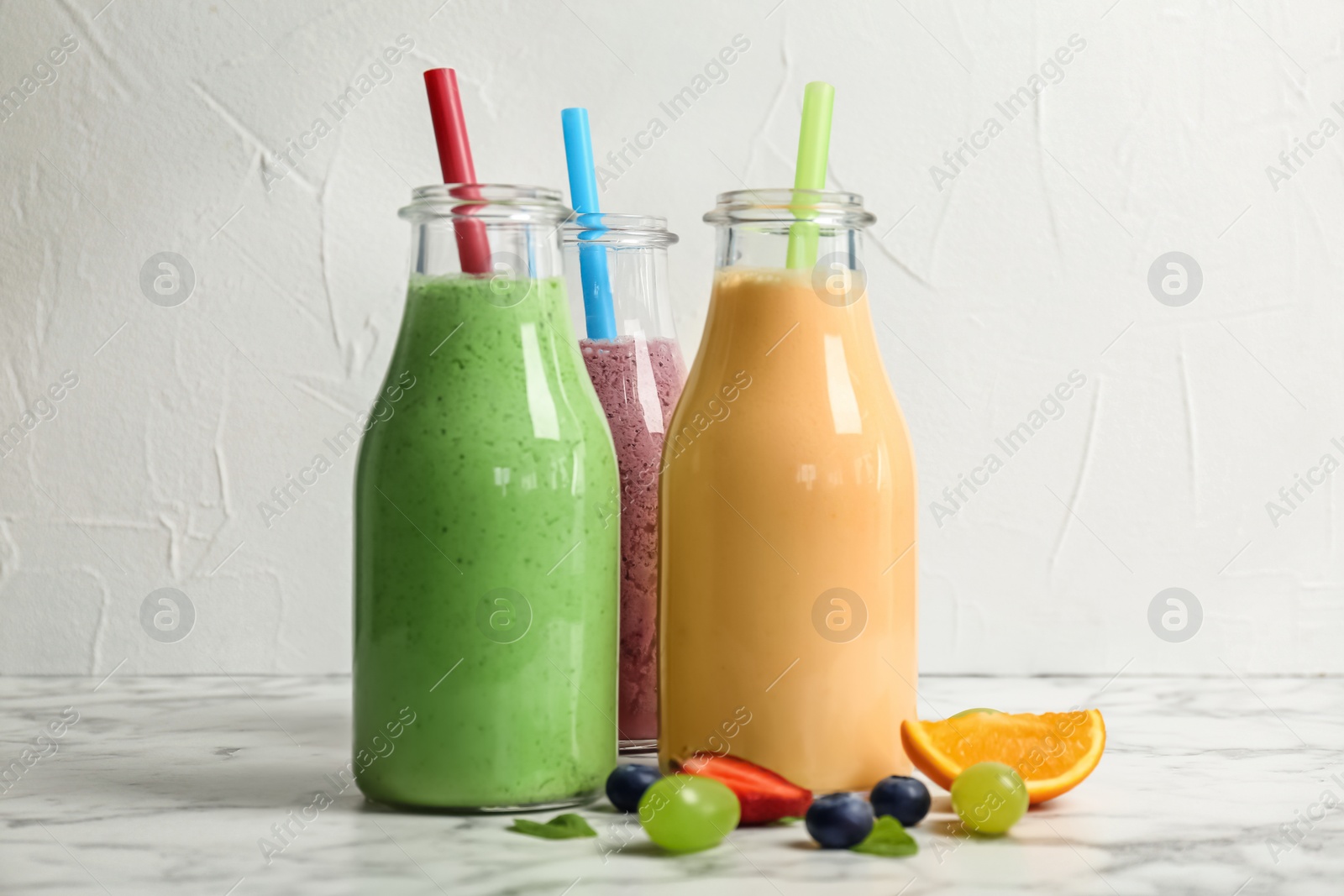 Photo of Bottles with healthy detox smoothies and ingredients on table