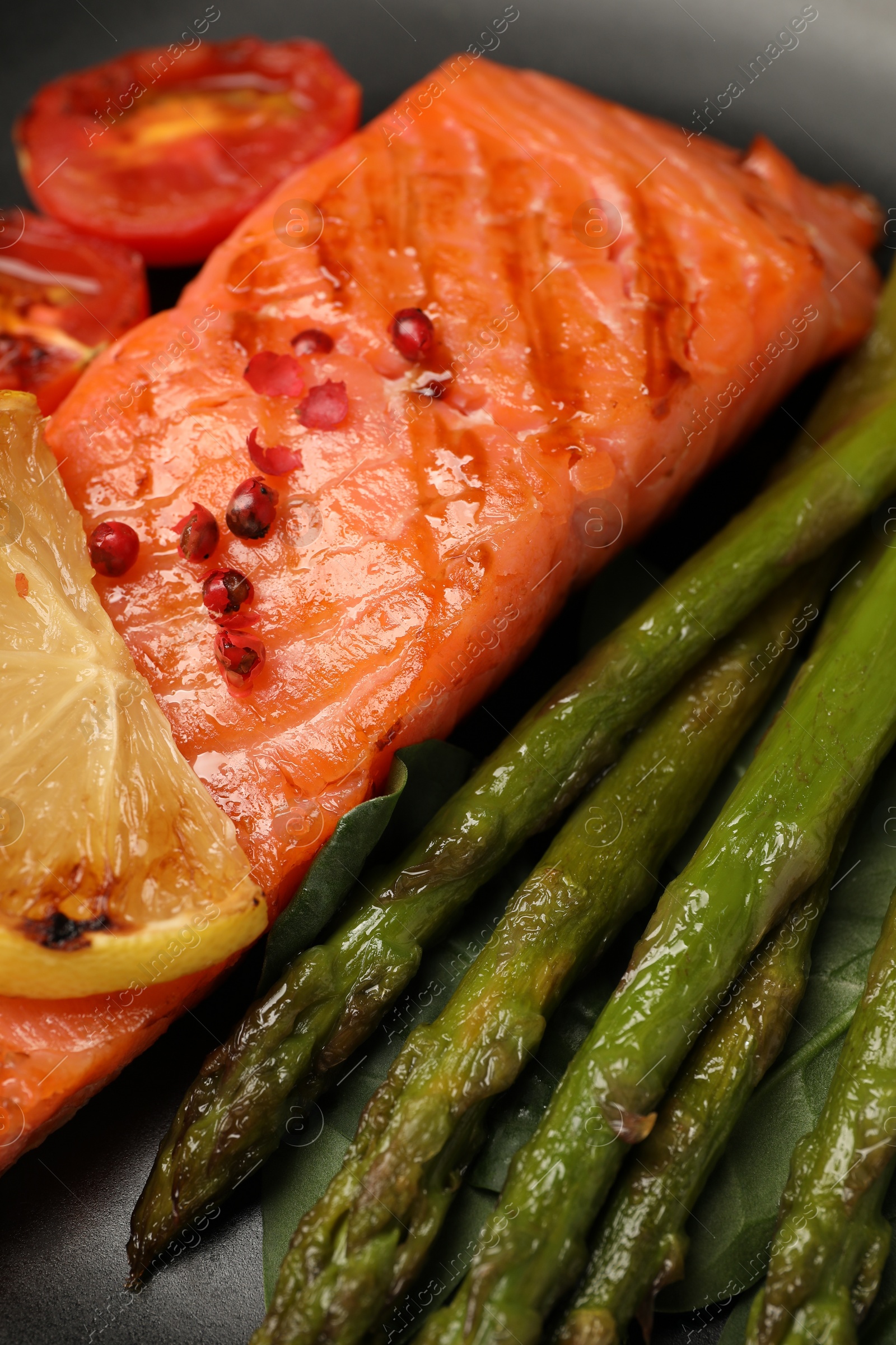 Photo of Tasty grilled salmon, lemon and asparagus, closeup