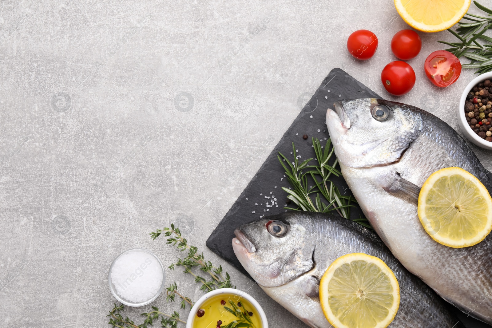 Photo of Flat lay composition with fresh raw dorado fish and ingredients on light grey table, space for text