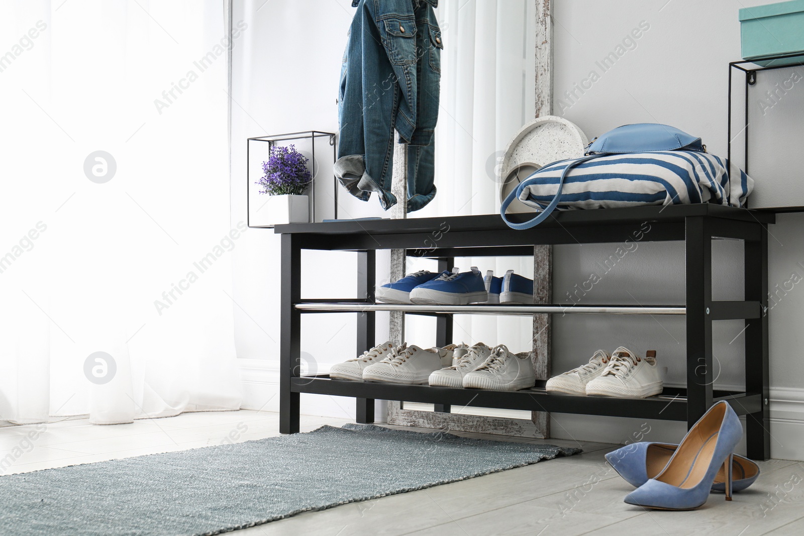 Stylish hallway interior with shoe rack and rug. Space for text Photo of Stylish hallway interior with shoe rack and rug. Space for text
