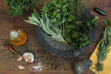 Photo of Mortar, different herbs, vegetables and oil on wooden table, flat lay