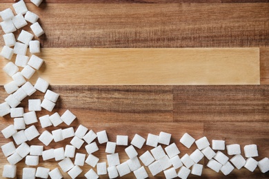 Refined sugar cubes on wooden background, top view