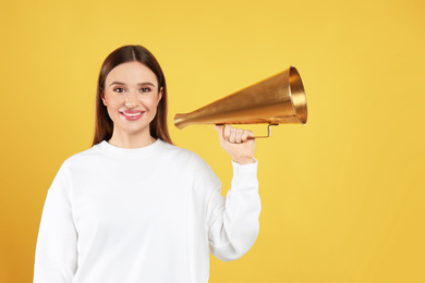 Photo of Young woman with vintage megaphone on yellow background
