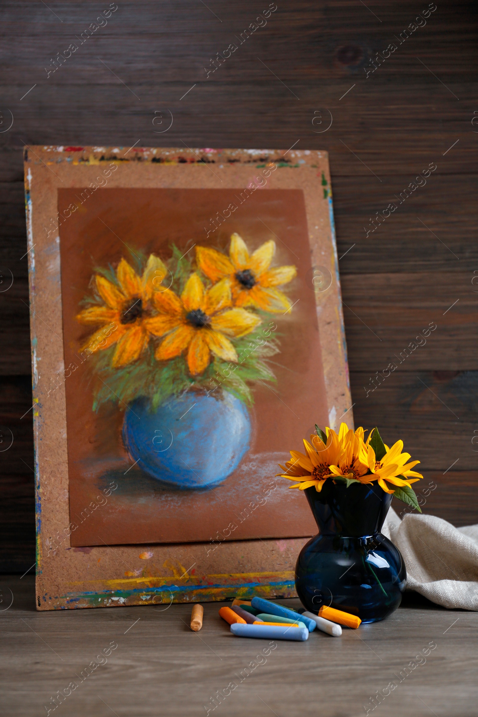 Photo of Yellow flowers, beautiful drawing and set of colorful pastels on wooden table