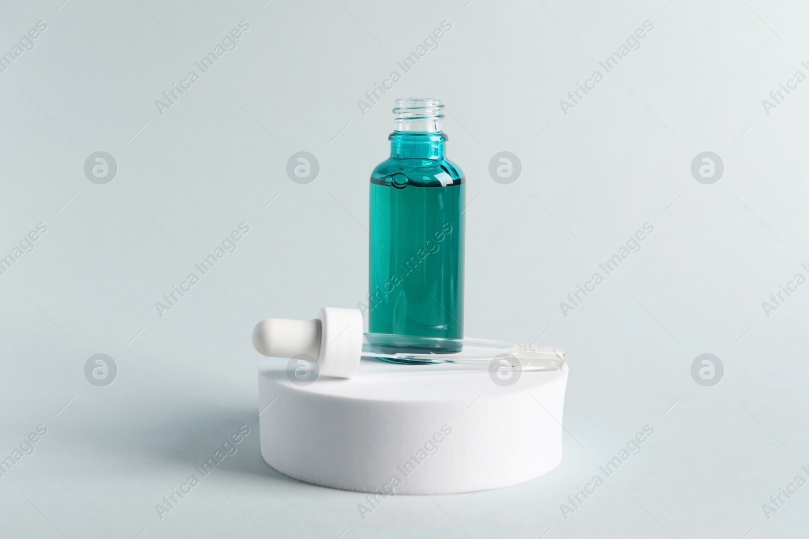 Photo of Bottle with cosmetic serum and pipette on light grey background