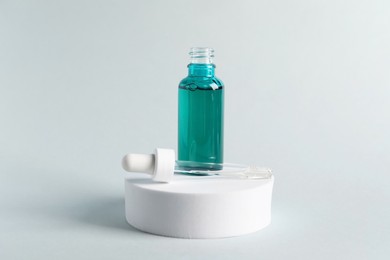 Photo of Bottle with cosmetic serum and pipette on light grey background