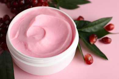 Photo of Fresh pomegranate and jar of facial mask on pink background, closeup. Natural organic cosmetics
