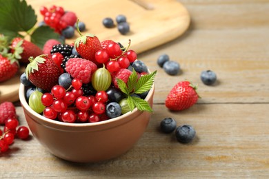 Photo of Mix of different fresh berries in bowl on wooden table. Space for text