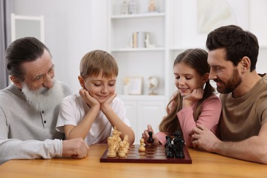 Family playing chess together at table in room