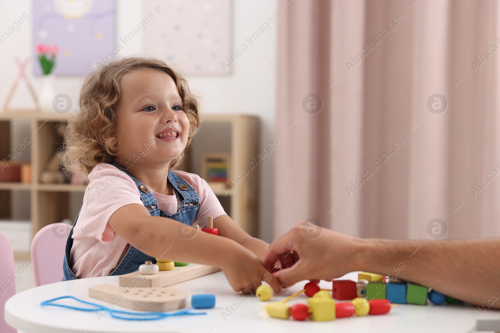 Photo of Motor skills development. Father and daughter playing with stacking and counting game at table indoors